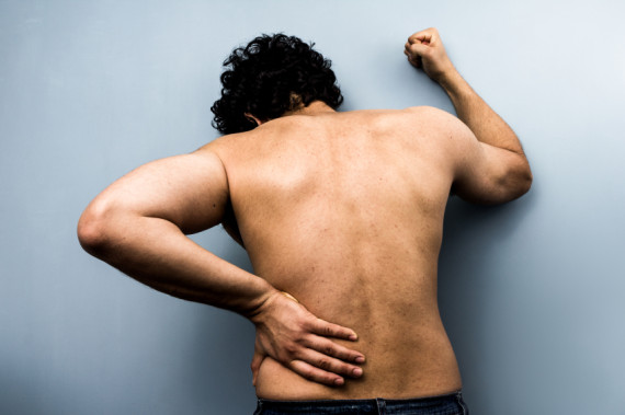 Young man with severe backpain from sciatica man holding his back in pain