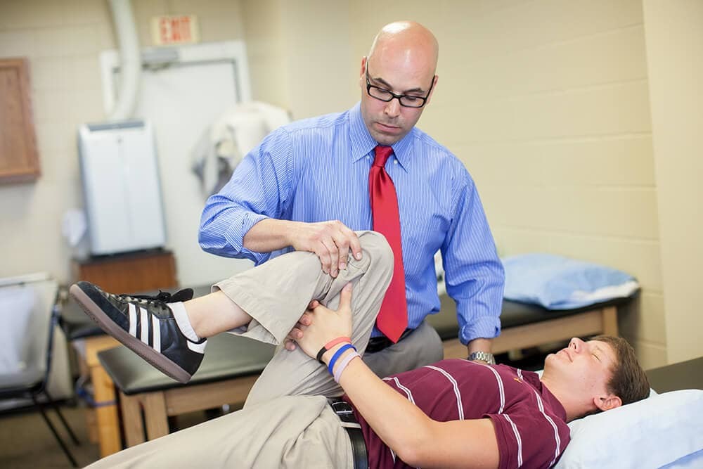 derek-sanchez-working-with-patient Physical therapist Derek Sanchez working with young male patient