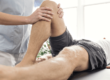 Physical therapist exercising leg of man with cerebral palsy