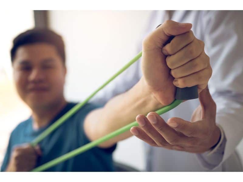 physical therapist helping a patient bend their arm