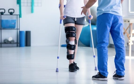 AdobeStock_224367549 physical therapist helping a patient with a leg injury