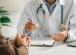 A man talks to a physician in a white coat about his physical therapy needs and coverage.