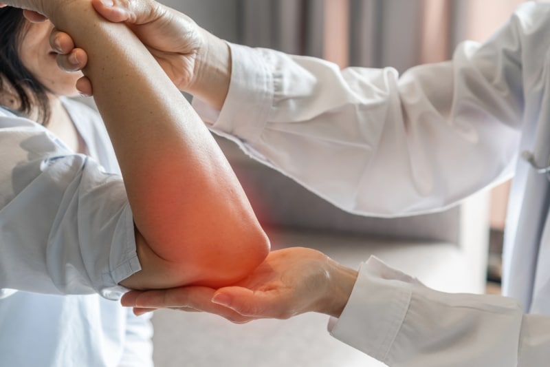 How Physical Therapy for Arthritis Can Help You Manage Pain Physical therapist exams elbow of physical therapy patient with arthritis pain.