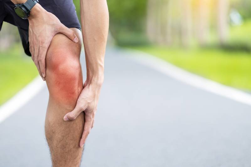 Male runner holding his injured knee.