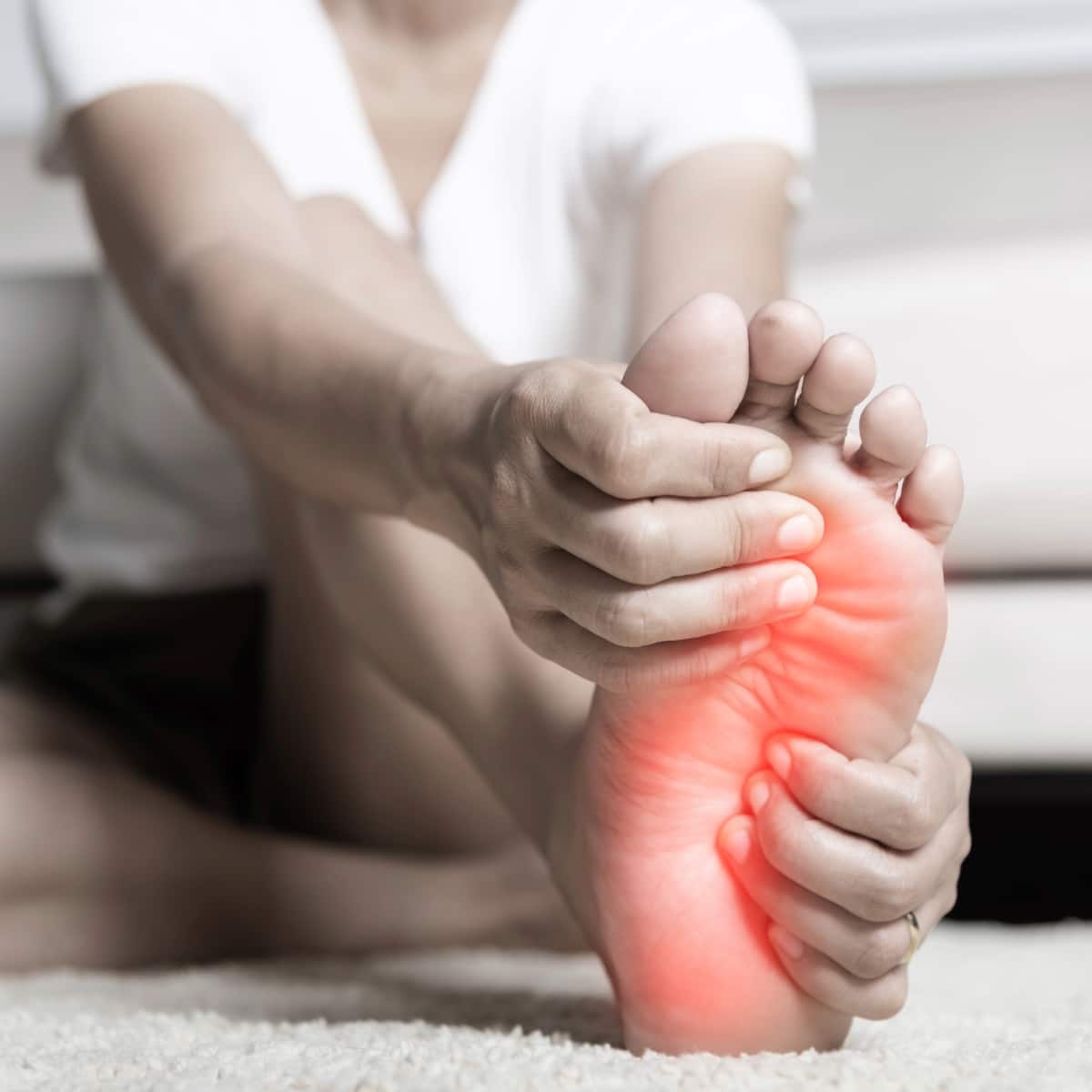 Person massaging painful foot with red highlight, indicating discomfort or foot pain relief.