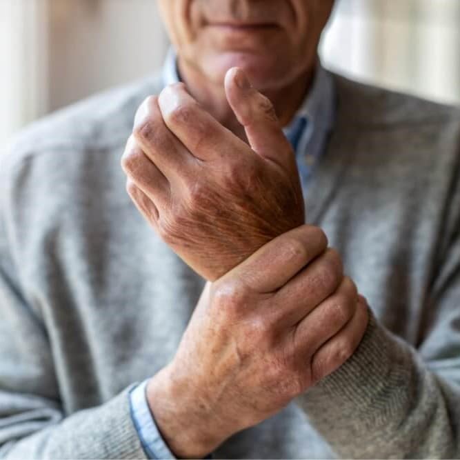 Older man holding his wrist in pain, possibly due to osteoporosis or joint problems.