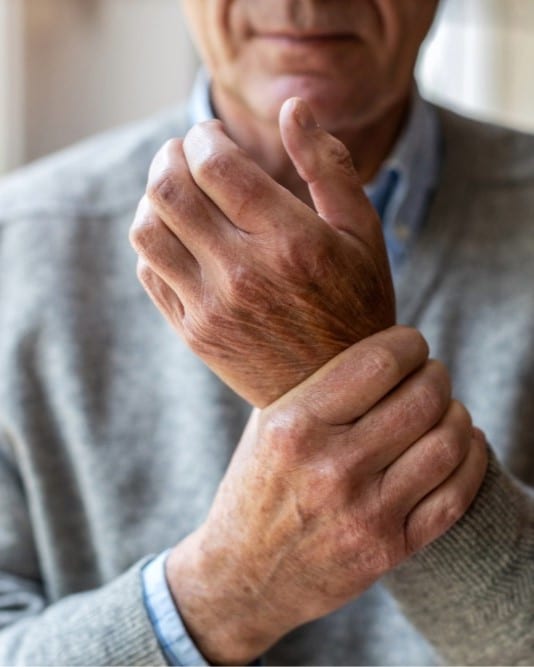Osteoporosis2 Older man holding his wrist in pain, possibly due to osteoporosis or joint problems.
