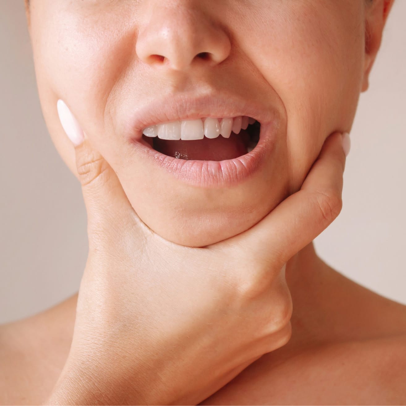 jaw-pain-2 Woman experiencing jaw pain, holding her cheek in pain, highlighting dental discomfort and oral health issues.