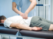 Manual therapist working with patient's back. The patient is laying face down on a table.