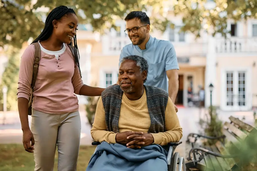 young woman with elder father on wheelchair and caregiver pushing wheelchair