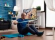 Older adult using a resistance band on an exercise mat during a virtual home therapy routine.